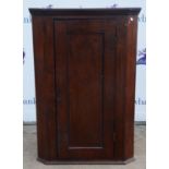 A Walnut corner cabinet,19th Century, with panel door enclosing shelves, 113cm high x 77cm wide x