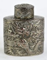 A Chinese white metal tea caddy and cover, decorated in high relief with dragons and waves,