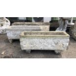 Pair of reconstituted stone troughs moulded with masks and scrolls on separate feet,