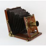 A folding mahogany plate camera by Barnett and Co., Johannesburg, with a brass lens, 23.5 x 20.5cm