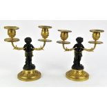 After Clodion, a pair patinated bronze and ormolu two light candelabra, cast as satyrs sitting on