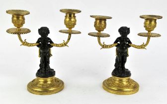 After Clodion, a pair patinated bronze and ormolu two light candelabra, cast as satyrs sitting on