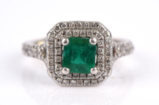An emerald and diamond ring, with a central emerald cut emerald, surrounded by two rows of round