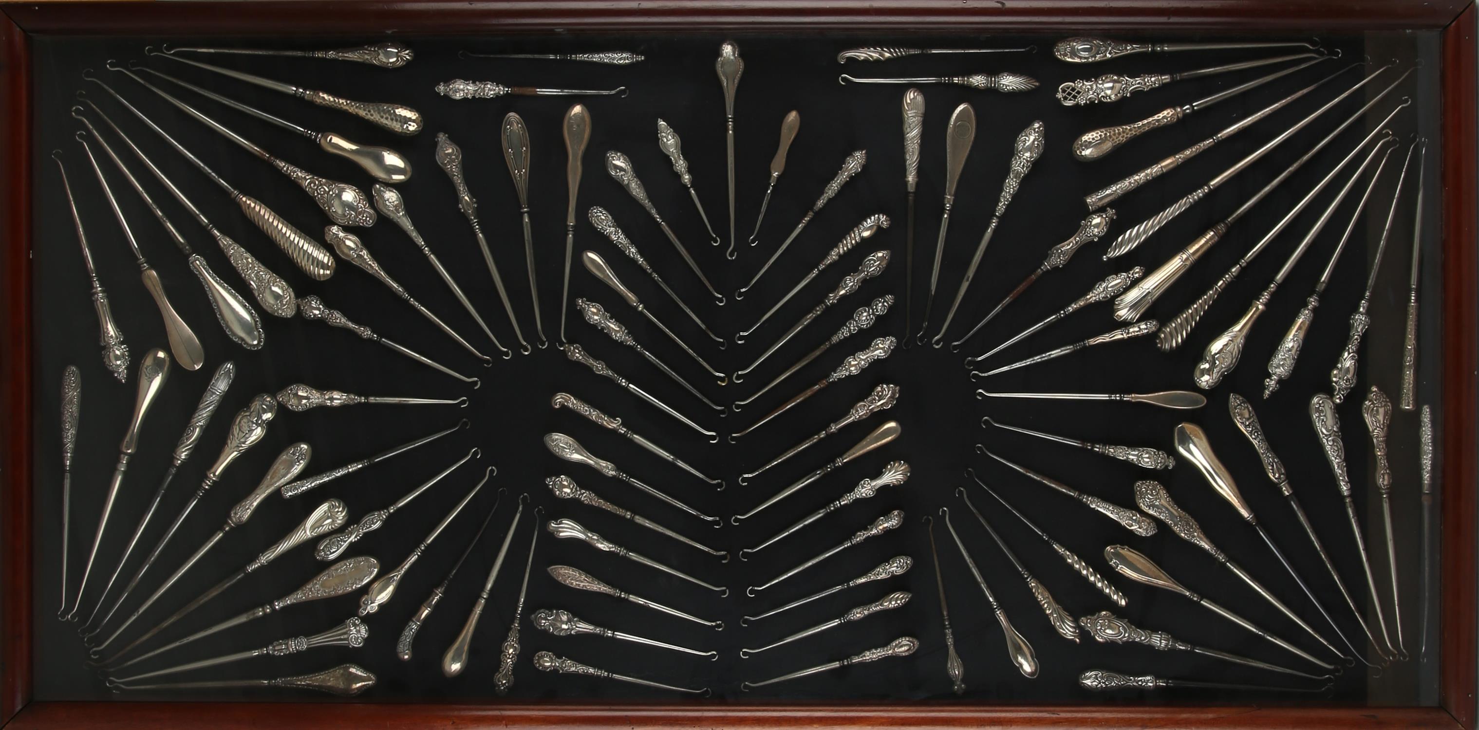 Three display cases, late 19th Century, displaying a large collection of silver button hooks,