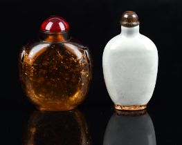 A glass Chinese snuff bottle with oval base, decorated with a gilt splashed design; about 8 cm