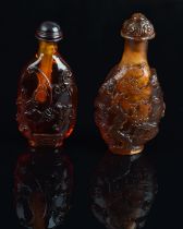 Two amber Chinese snuff bottles; one decorated with figures and one decorated with natural history