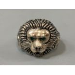 A silver ring with lion mask decoration set with emerald eyes, weight 9.33 grams