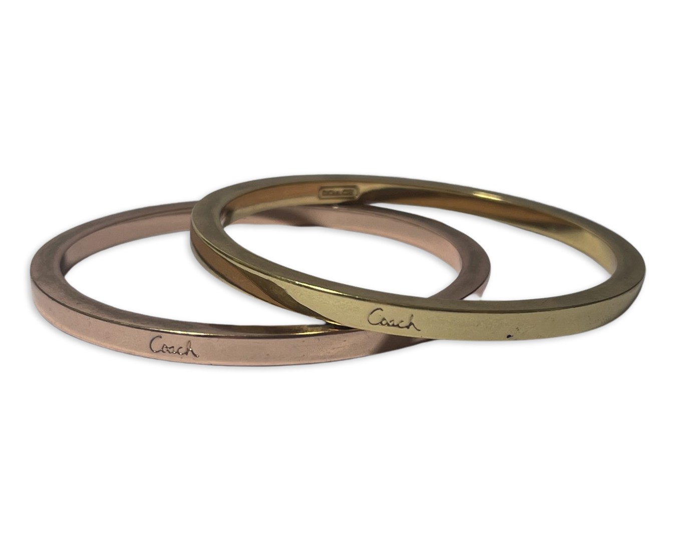 Pair of bangles by Coach, one gold tone and the other rose, weighing 73.3 grams collectively