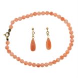 A pair of coral drop earrings and a coral bead bracelet.