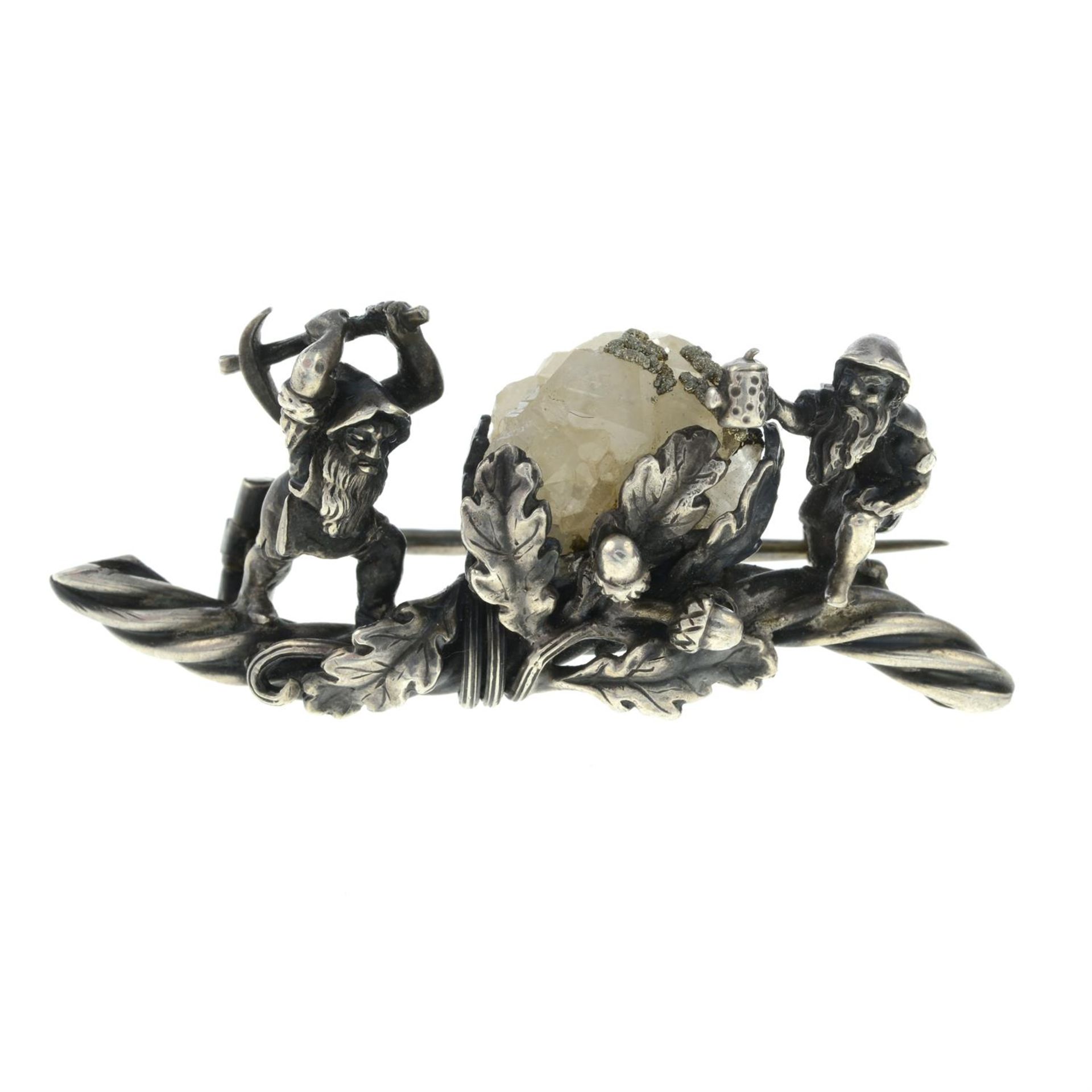 A late 19th century bar brooch, depicting two dwarves mining a pyrite laden quartz crystal,