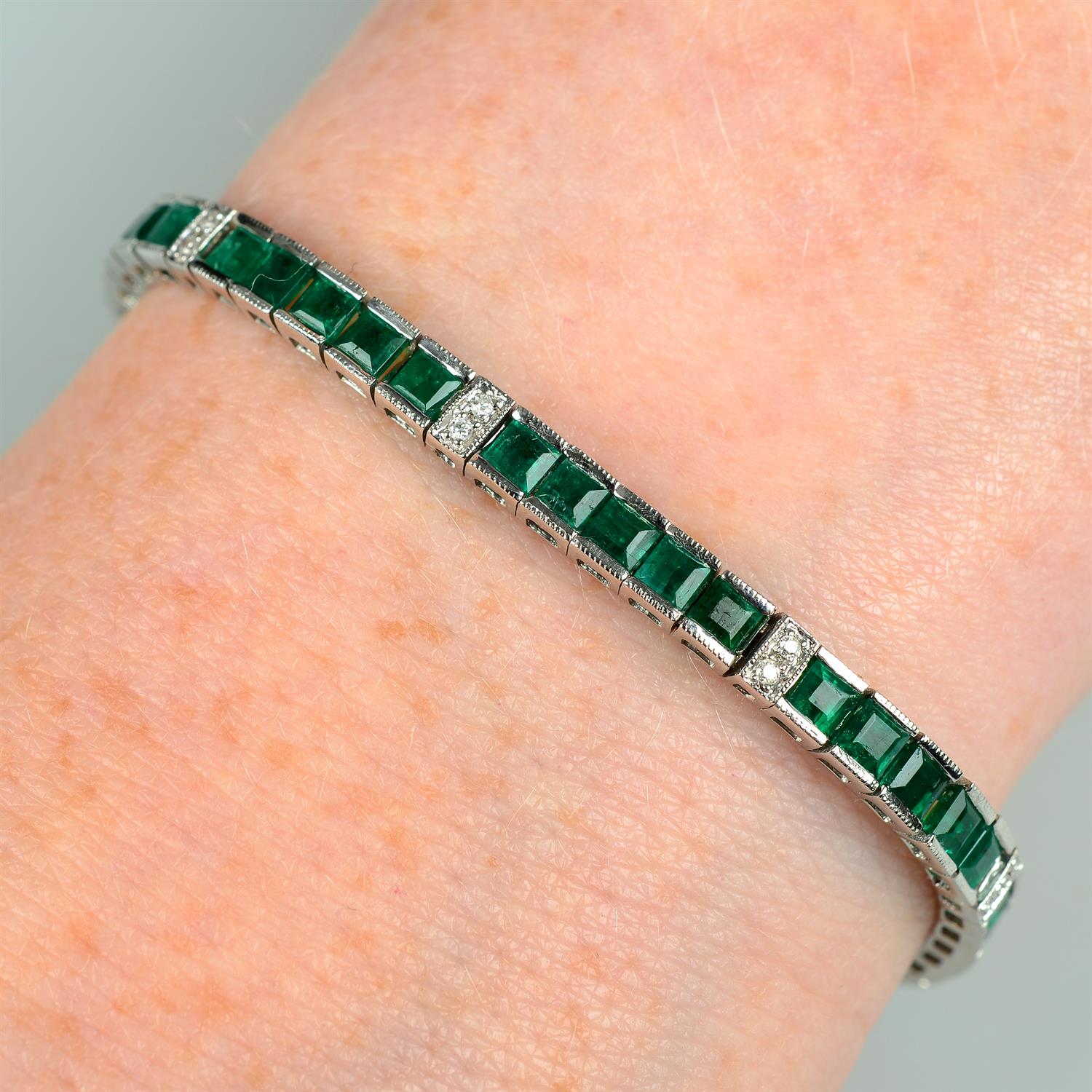 An emerald line bracelet, with brilliant-cut diamond spacers.