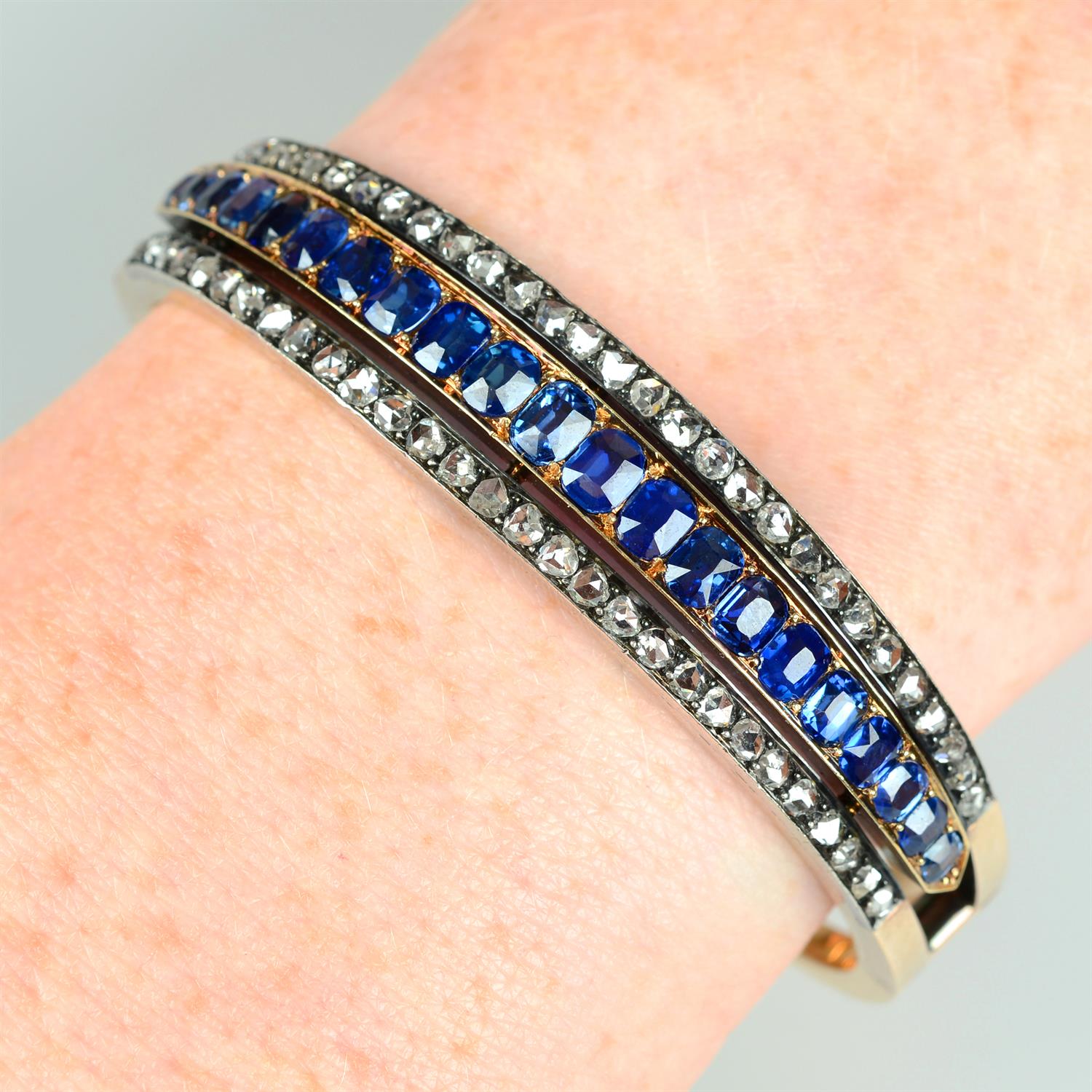 A late 19th century silver and 18ct gold sapphire and rose-cut diamond hinged bangle.
