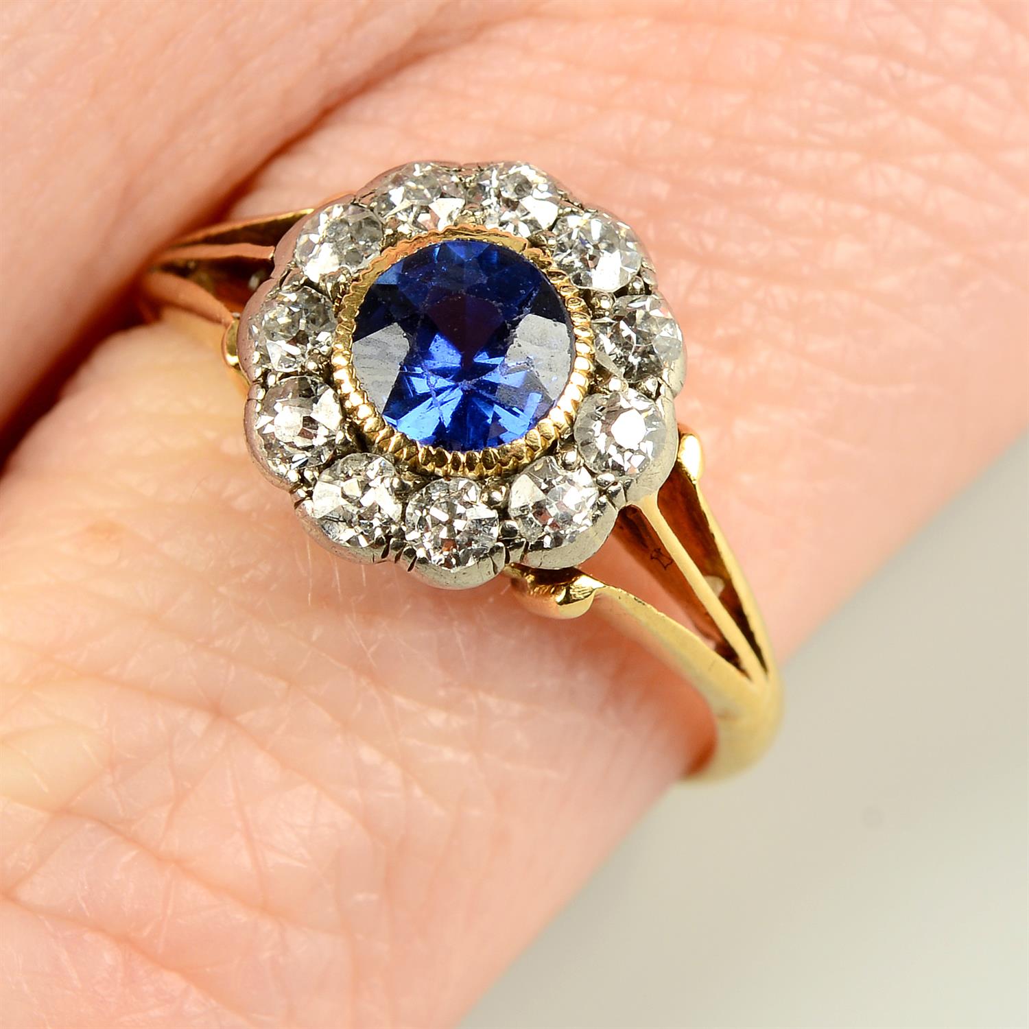 An early 20th century gold sapphire and old-cut diamond cluster ring, with openwork shoulders.