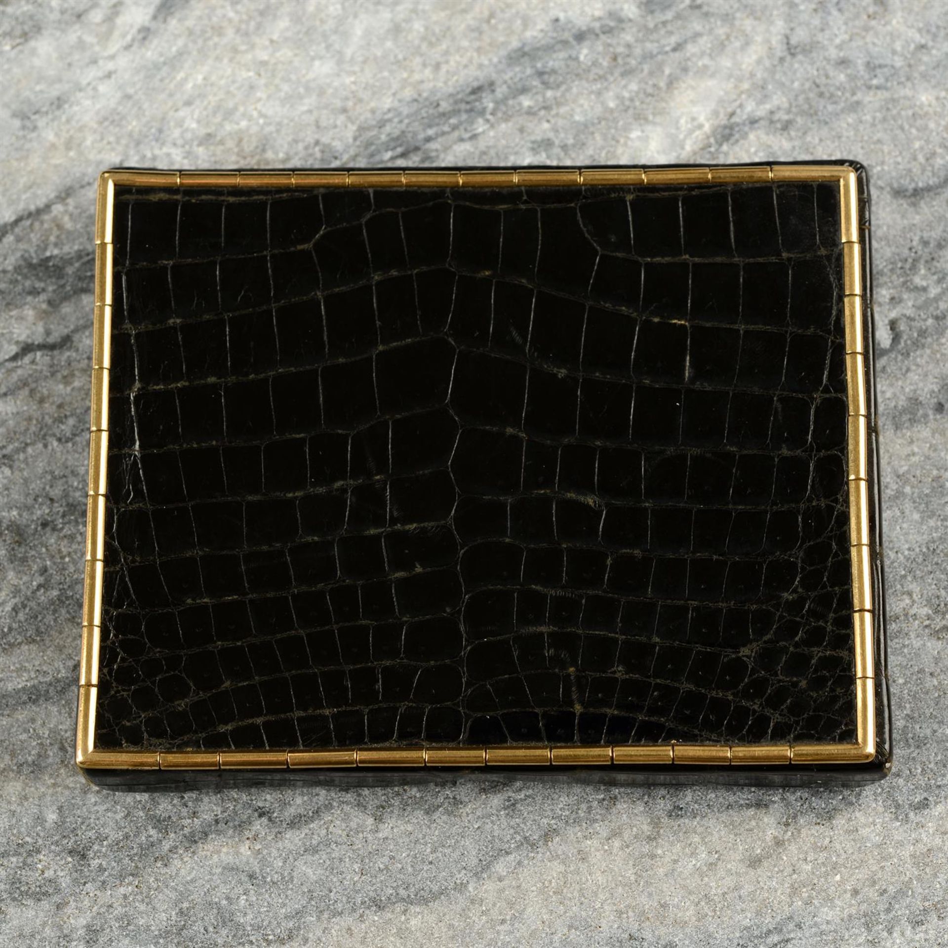 A mid 20th century 9ct gold mounted crocodile skin cigarette case, by Cartier.