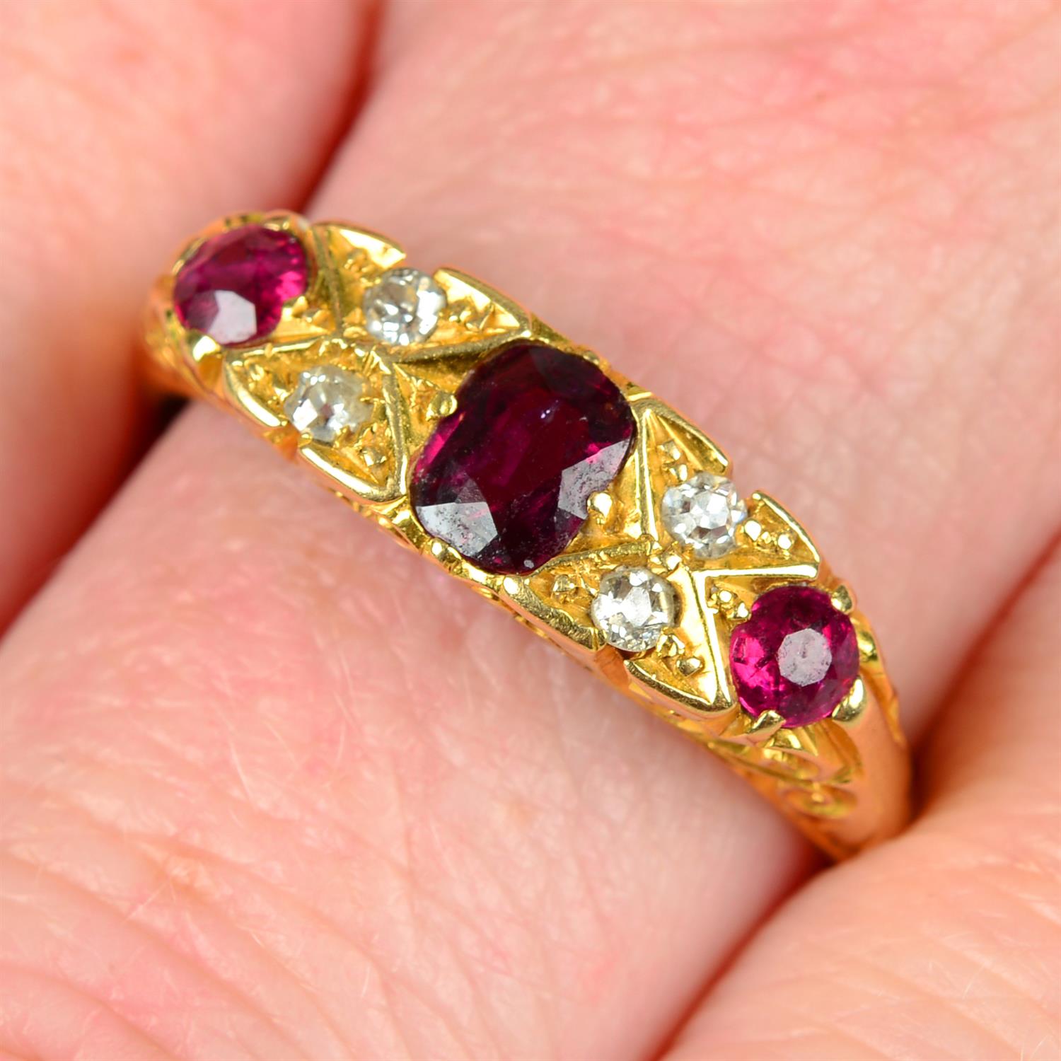 An early 20th century 18ct gold graduated ruby three-stone ring, with diamond spacers.