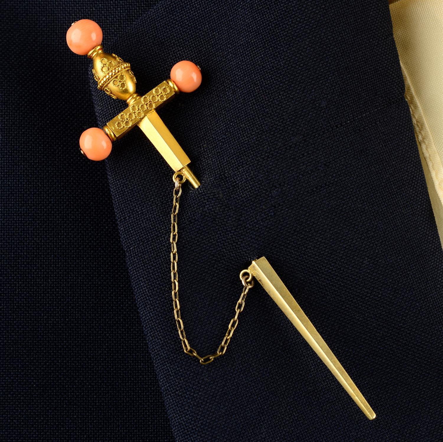 A mid to late 19th century gold cannetille sword pin, with coral bead highlights.