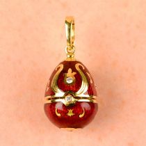 A limited edition 18ct gold diamond and red enamel hinged egg pendant, containing a treble clef,