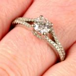 A brilliant-cut diamond single-stone ring, with diamond shoulders.