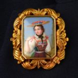 An early to mid 19th century gold painted porcelain portrait brooch, depicting a girl in Tyrolean