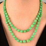 An early to mid 20th century graduated two-row jadeite jade bead necklace, with 15ct gold carved