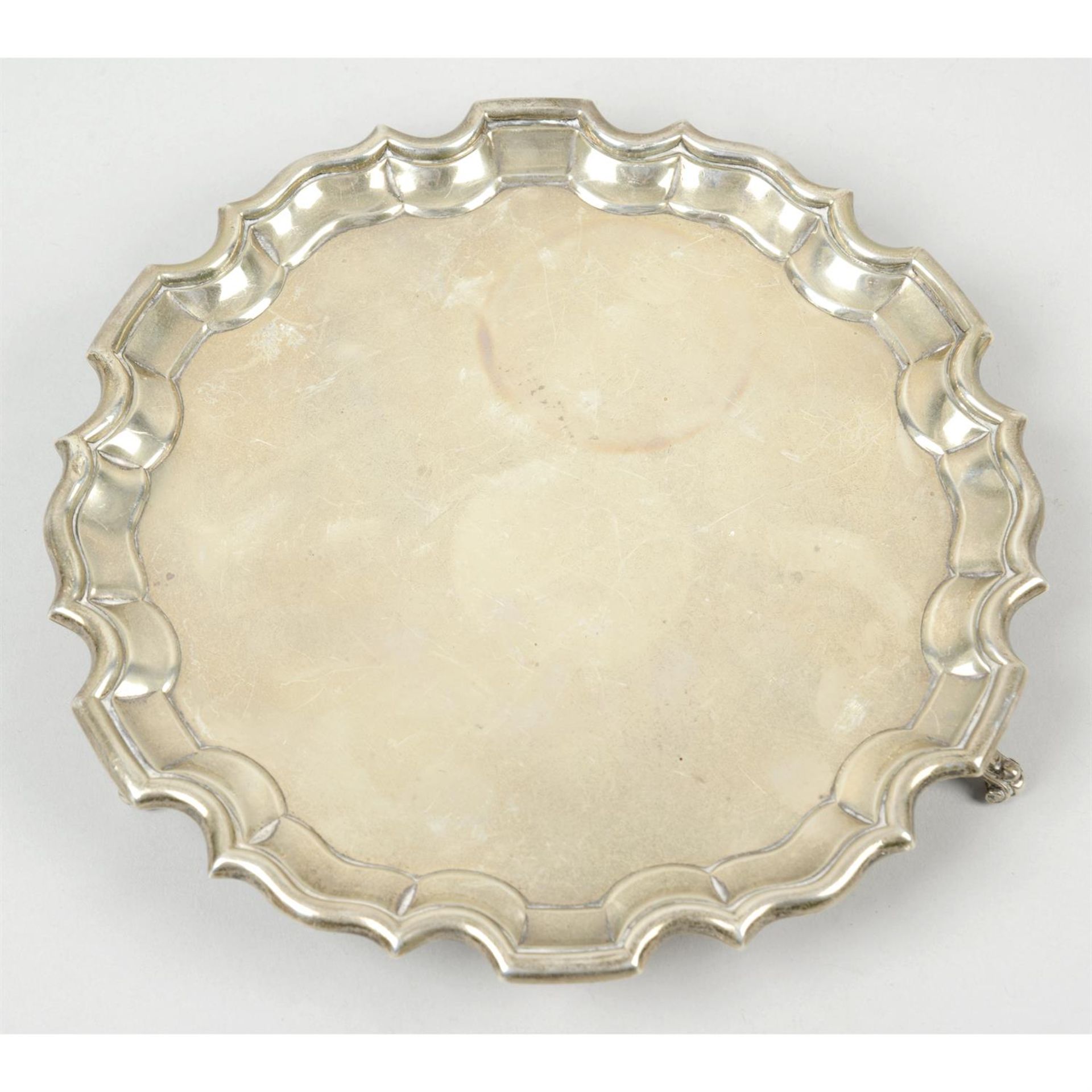 A 1930's small silver salver on scrolled feet.