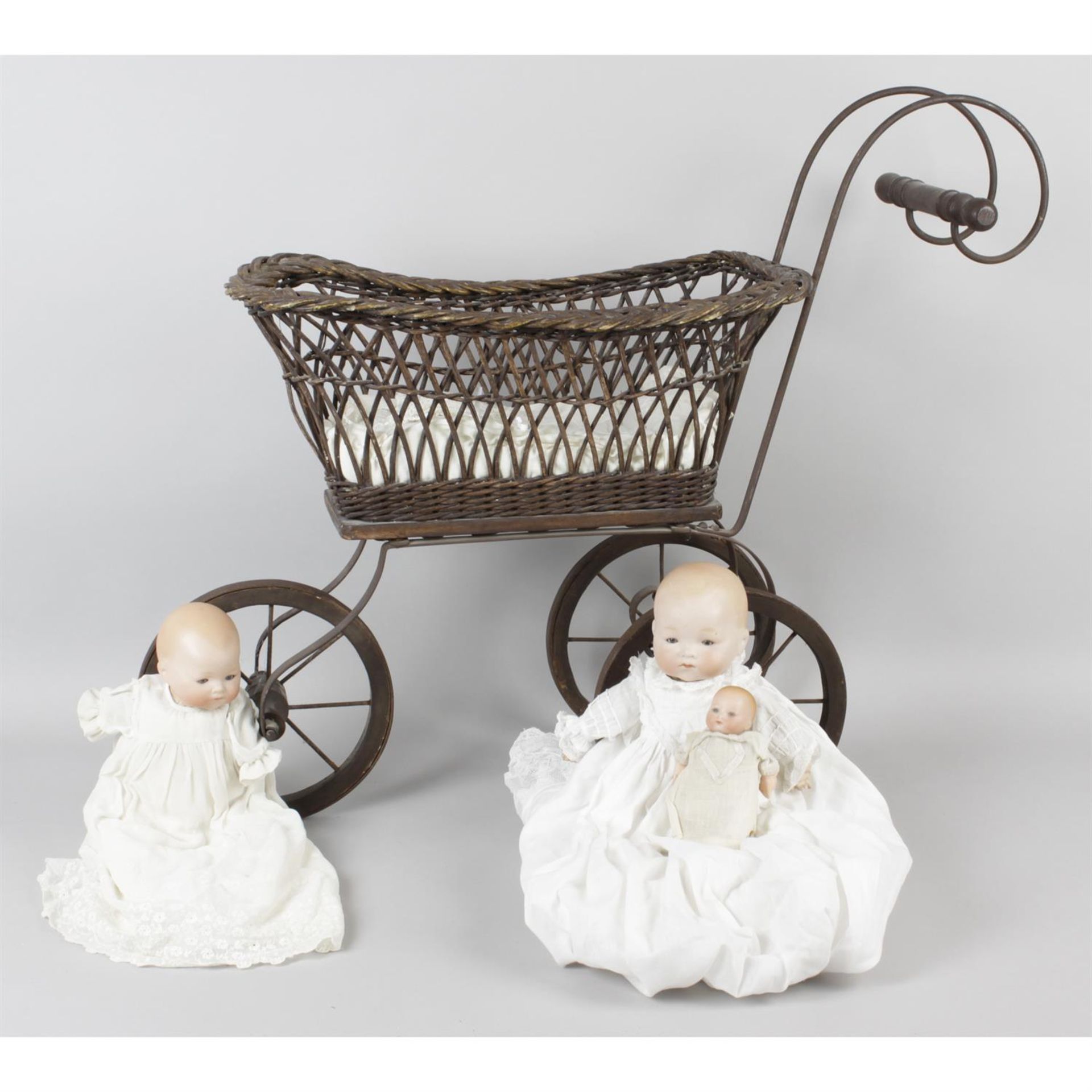 A reproduction wooden and wicker bodied dolls pram, together with a mahogany dolls crib and three