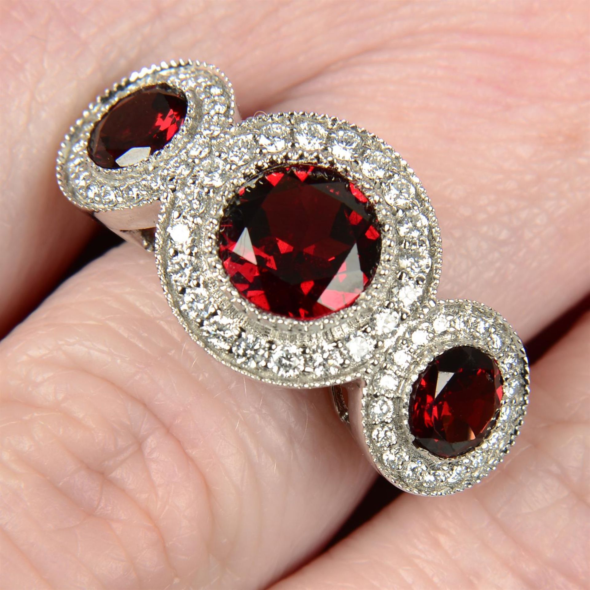 An 18ct gold garnet and brilliant-cut diamond triple cluster ring.