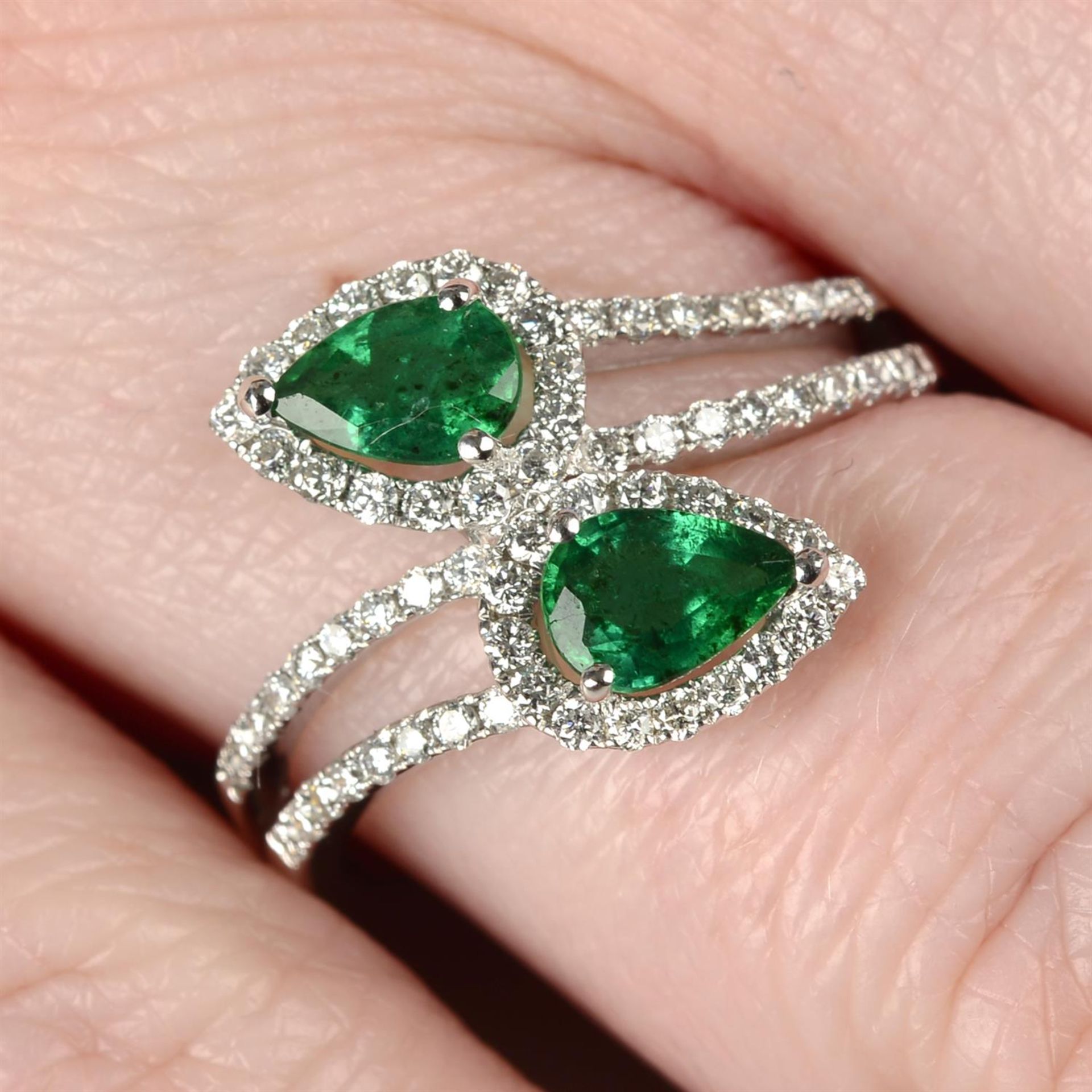 An emerald and brilliant-cut diamond crossover ring.