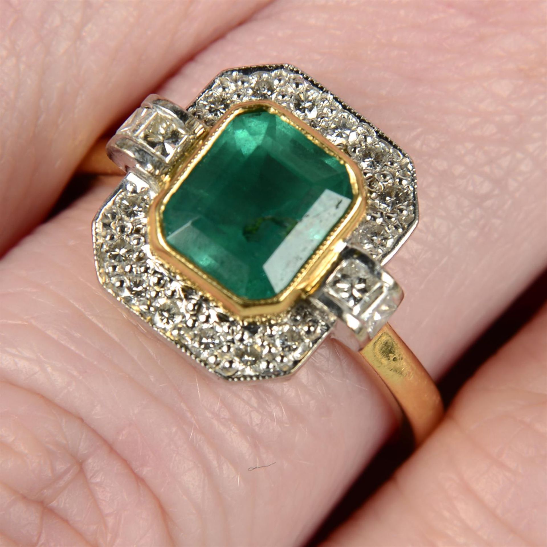 An 18ct gold emerald and vari-cut diamond dress ring.