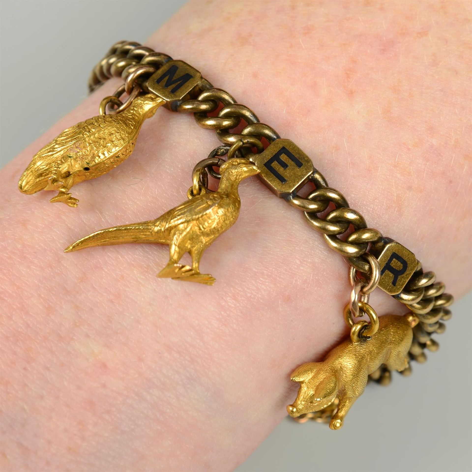 An early 20th century 18ct gold curb-link bracelet, with three enamel initial panel spacers reading