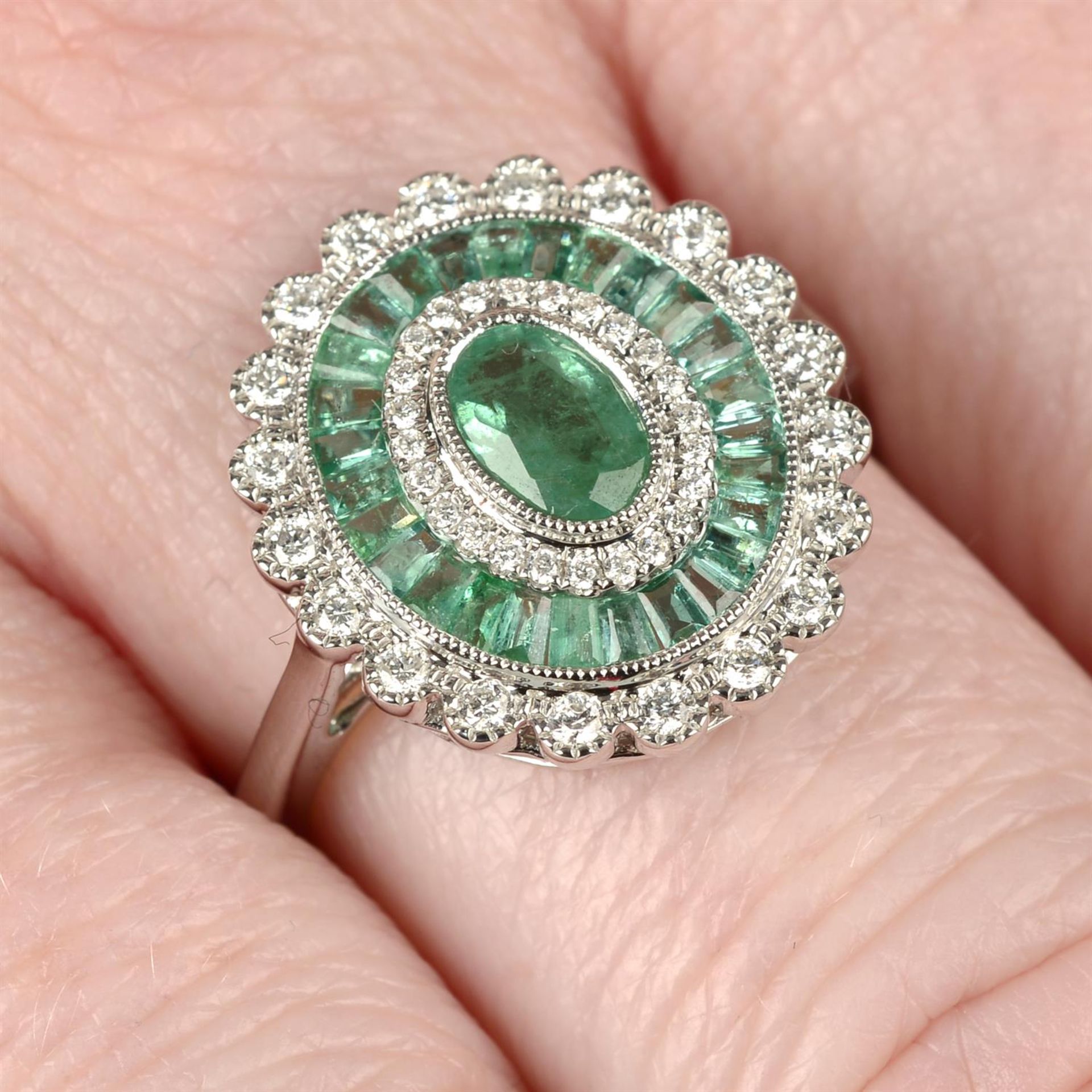 An 18ct gold emerald and diamond cluster ring.