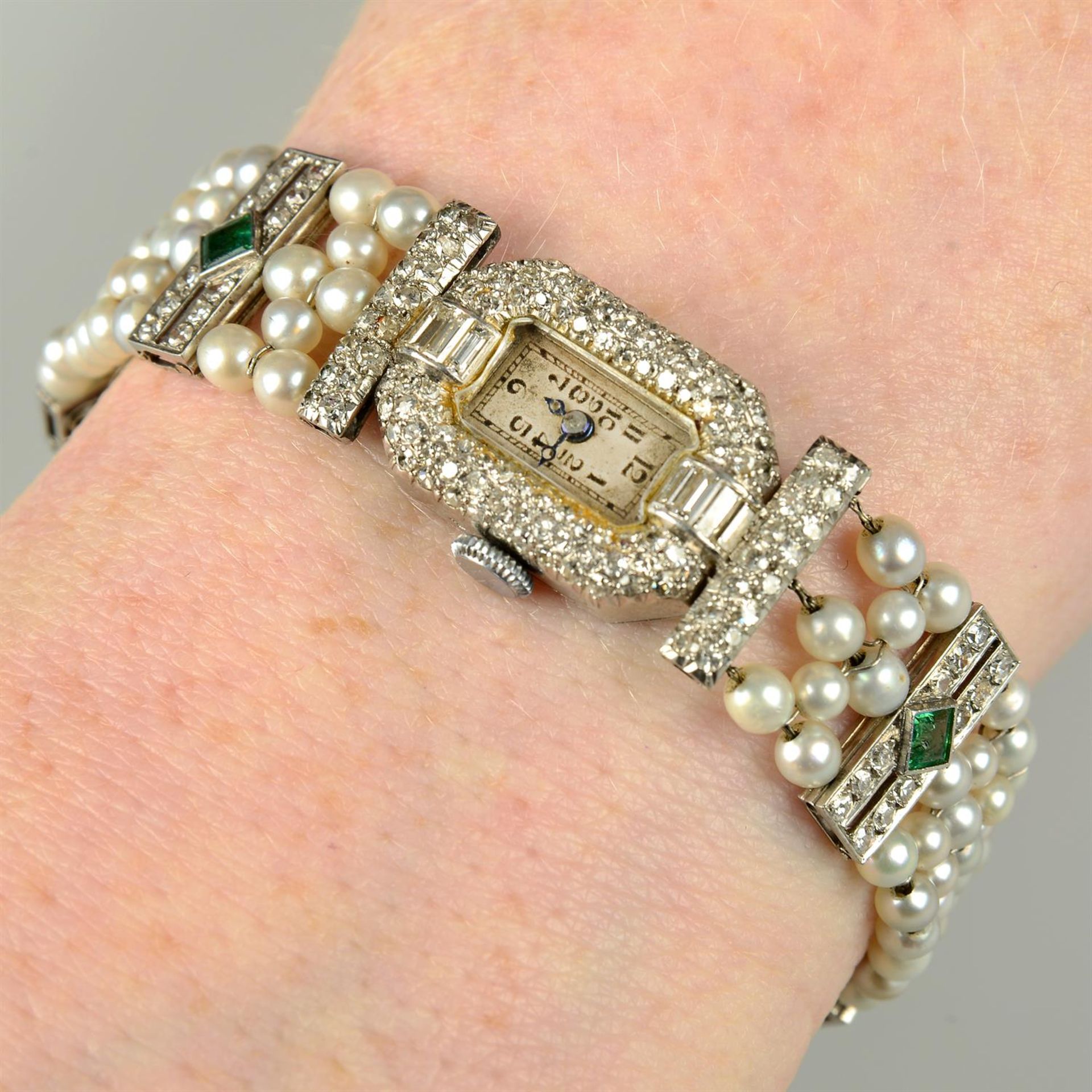 A lady's Art Deco platinum and 18ct gold vari-cut diamond, emerald and seed pearl wrist watch.