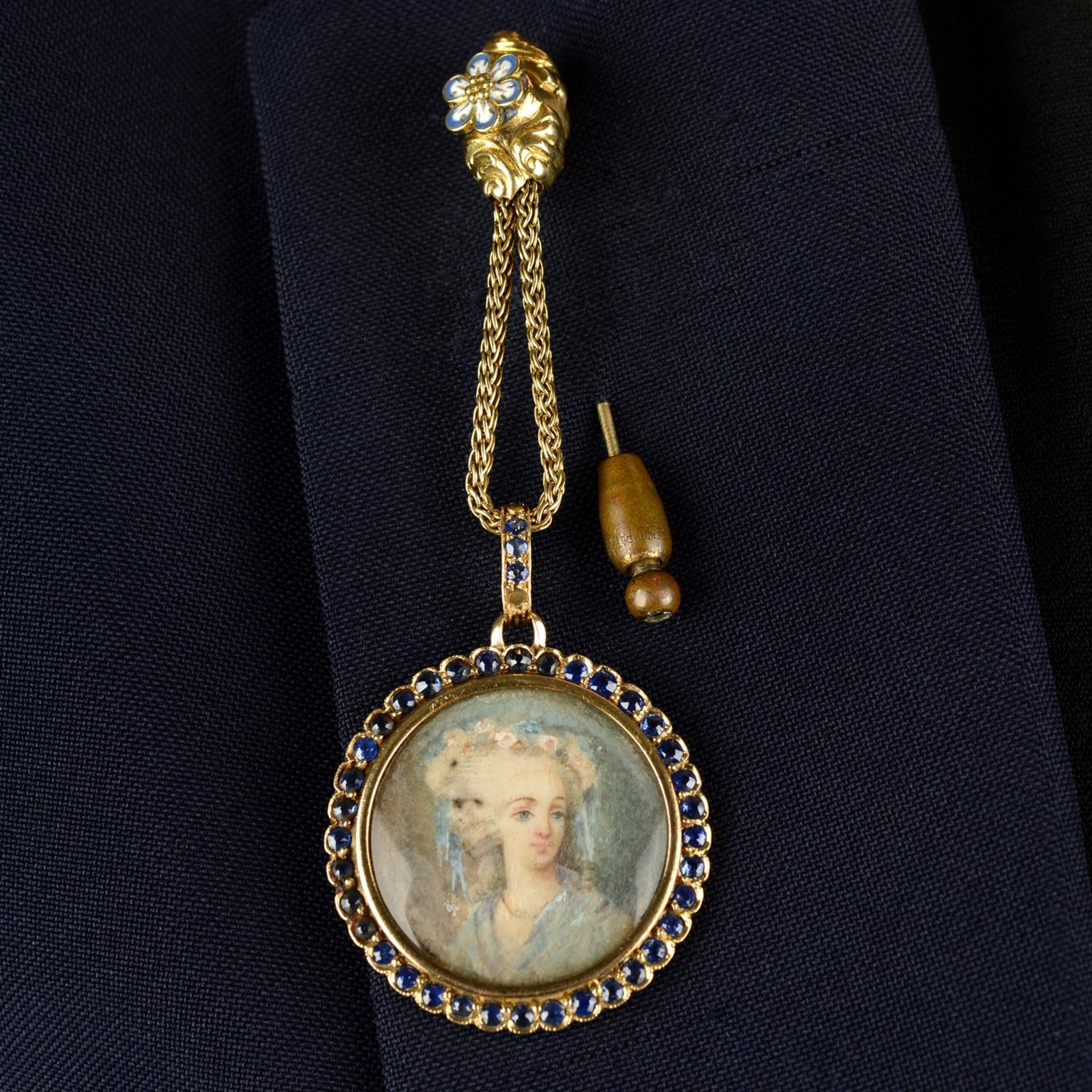 A late 19th century silver and 18ct gold sapphire mounted glazed locket, with painting depicting a