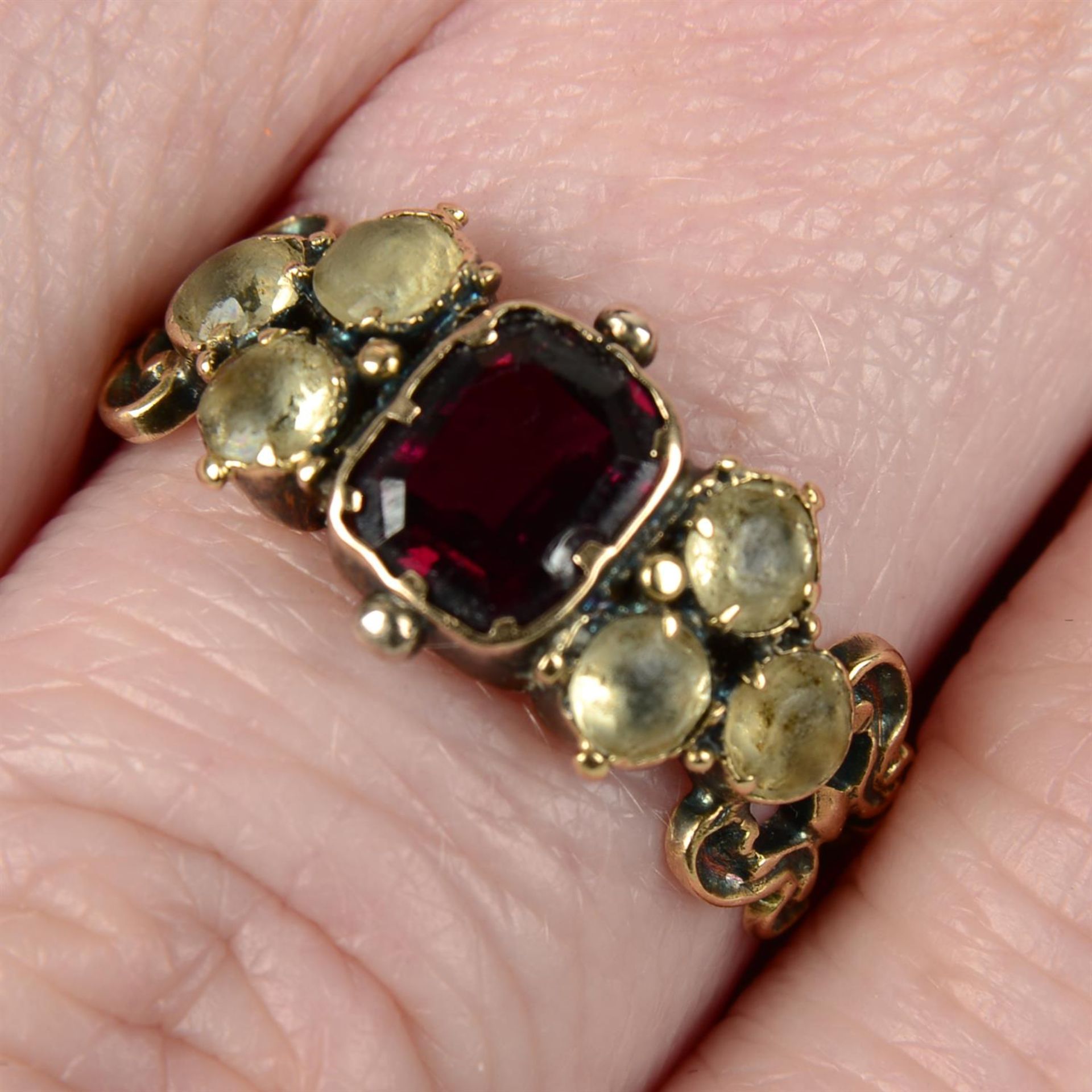 An early to mid 19th century gold garnet and chrysoberyl ring, with scrolling shoulders.