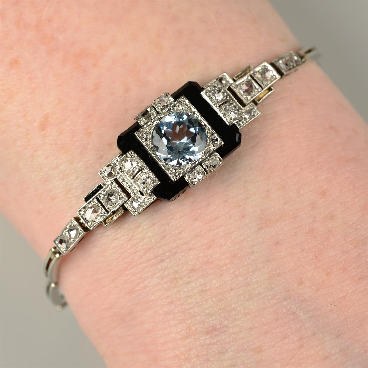 An Art Deco platinum and gold blue topaz, onyx and vari-cut diamond bracelet.