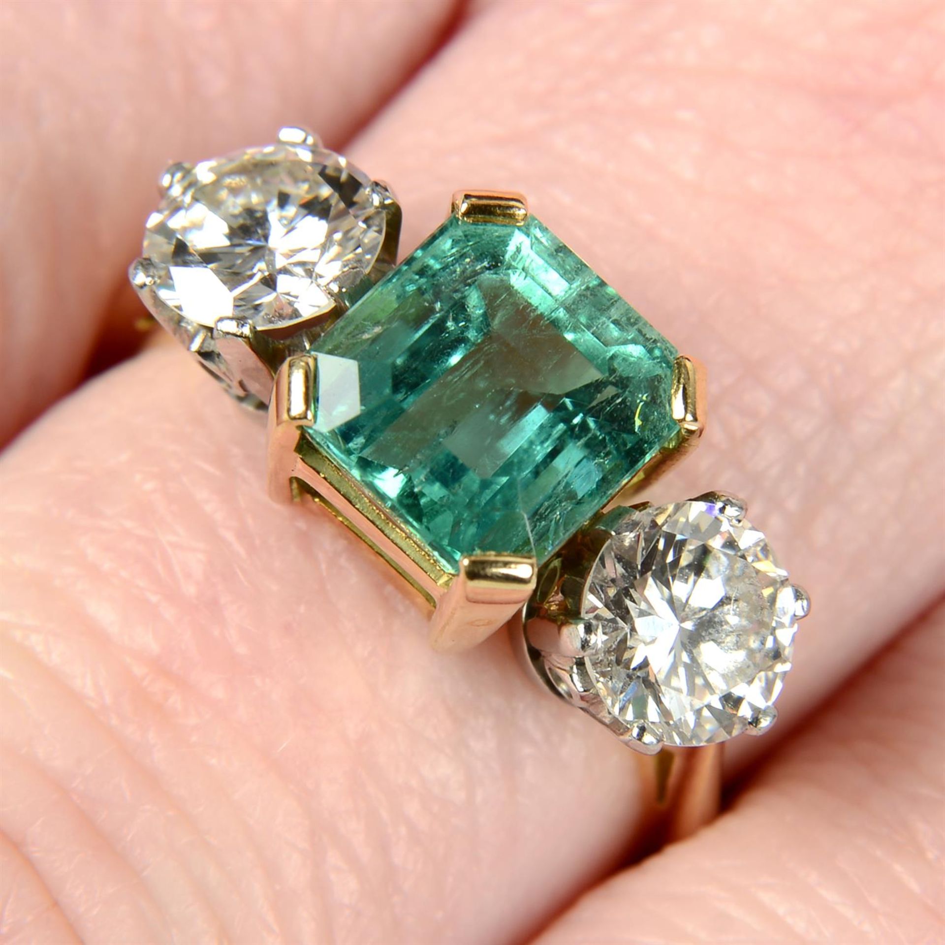 An 18ct gold emerald and brilliant-cut diamond three-stone ring.