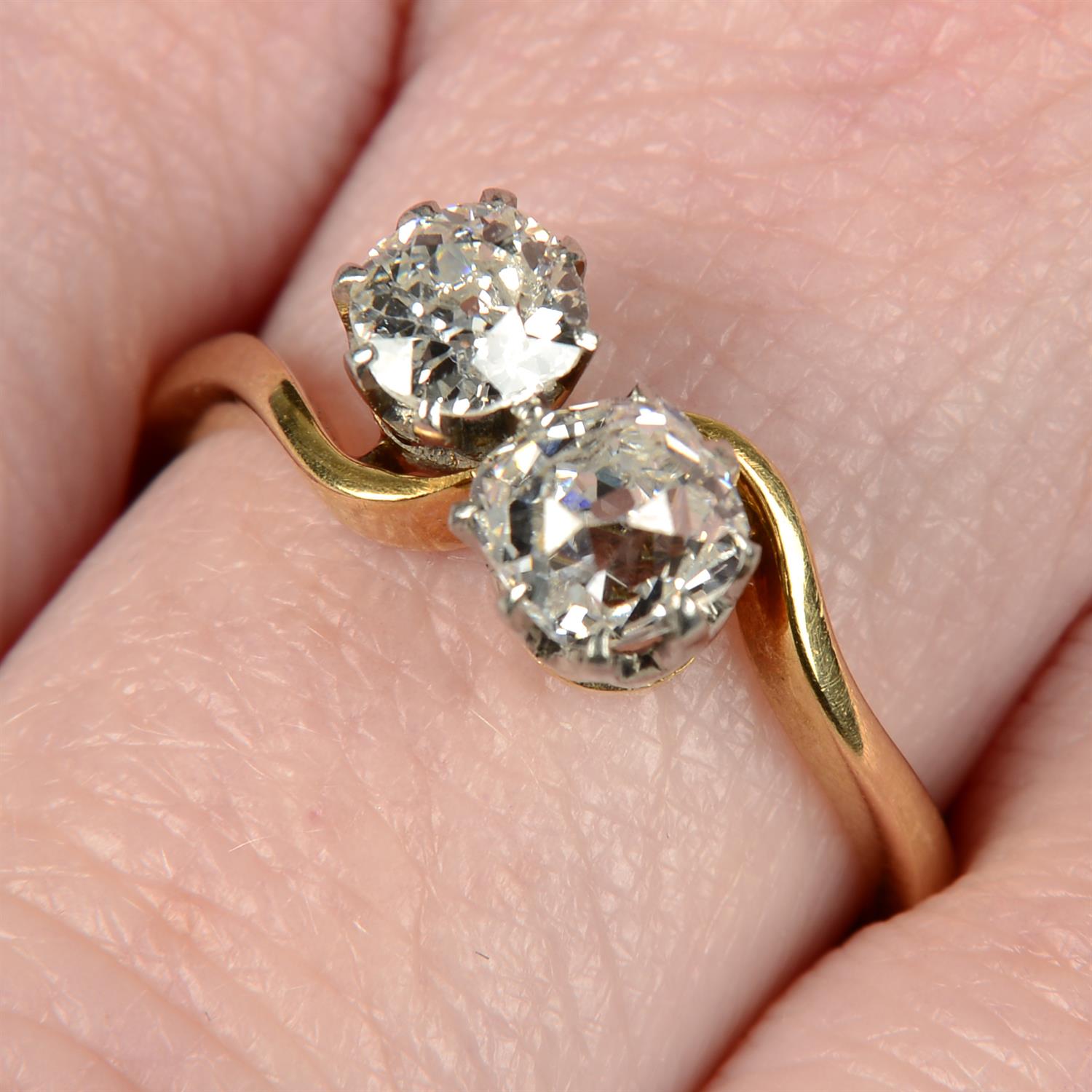 An early 20th century 18ct gold old-cut diamond two-stone crossover ring.