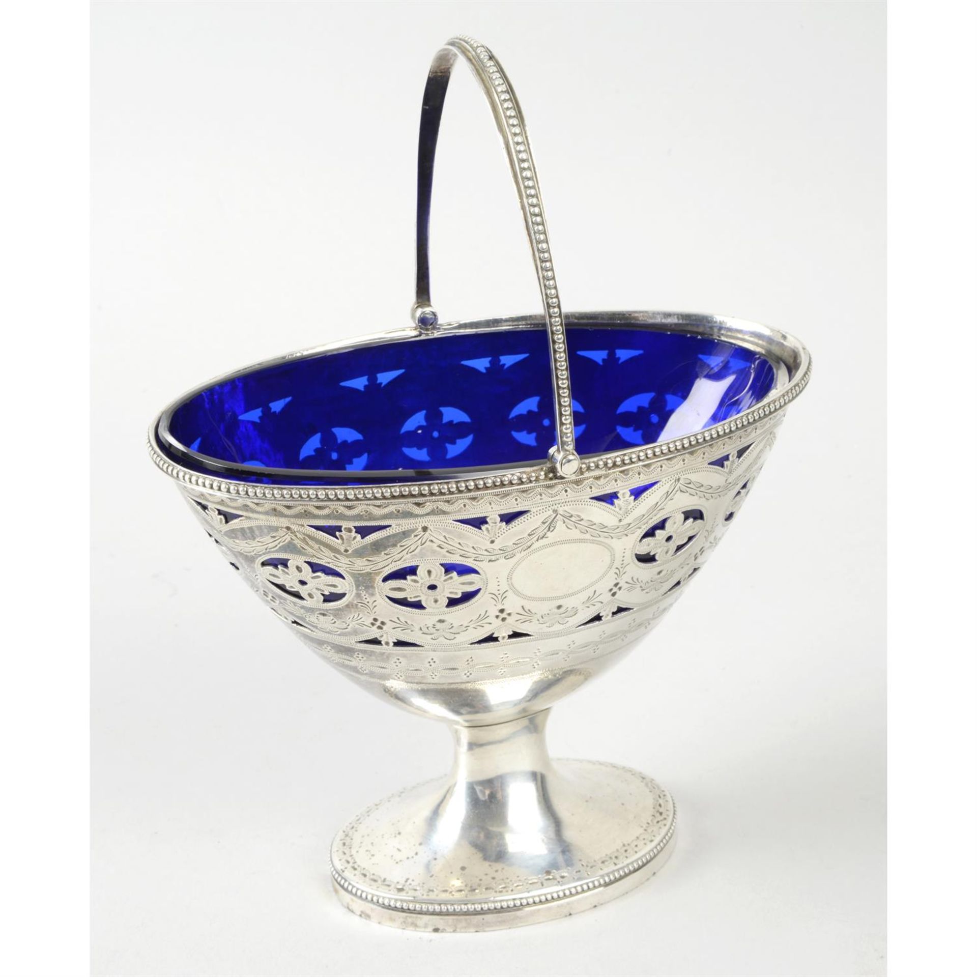 A George III silver swing-handled sugar basket with blue glass liner.