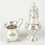 An Edwardian silver sugar caster; together with a 1920's silver cream jug. (2).