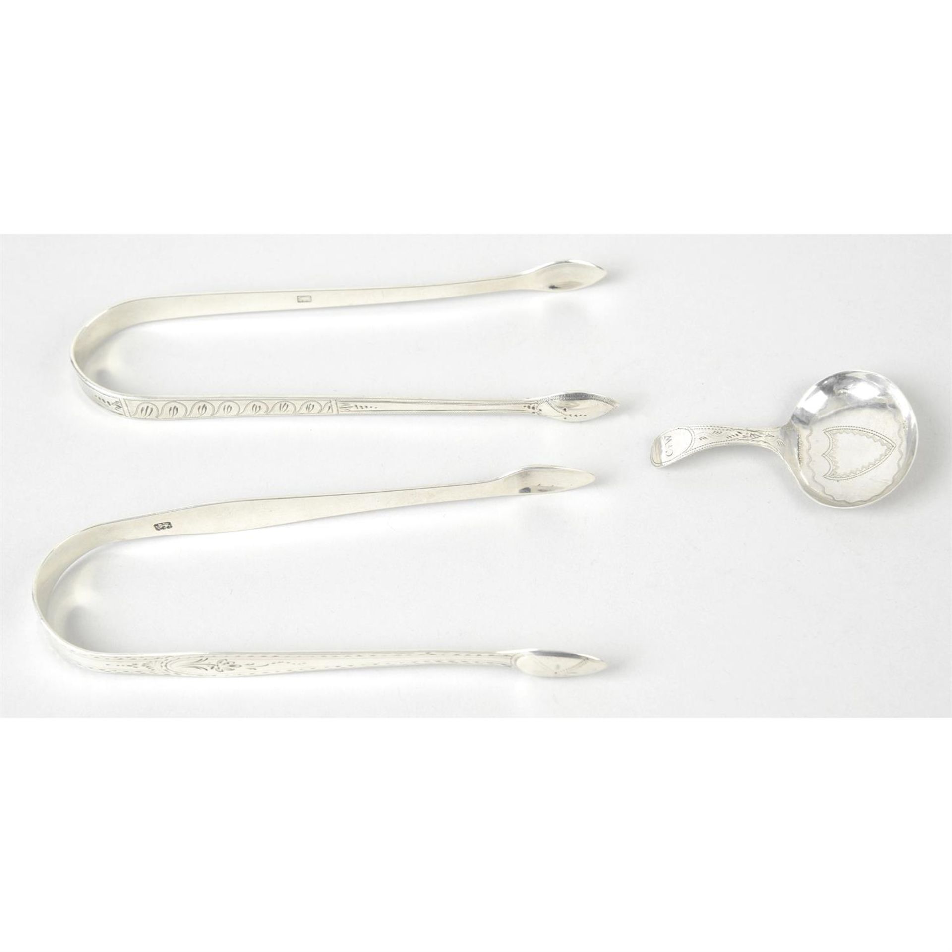 Two pairs of George III silver bright-cut engraved sugar tongs; together with a George III silver