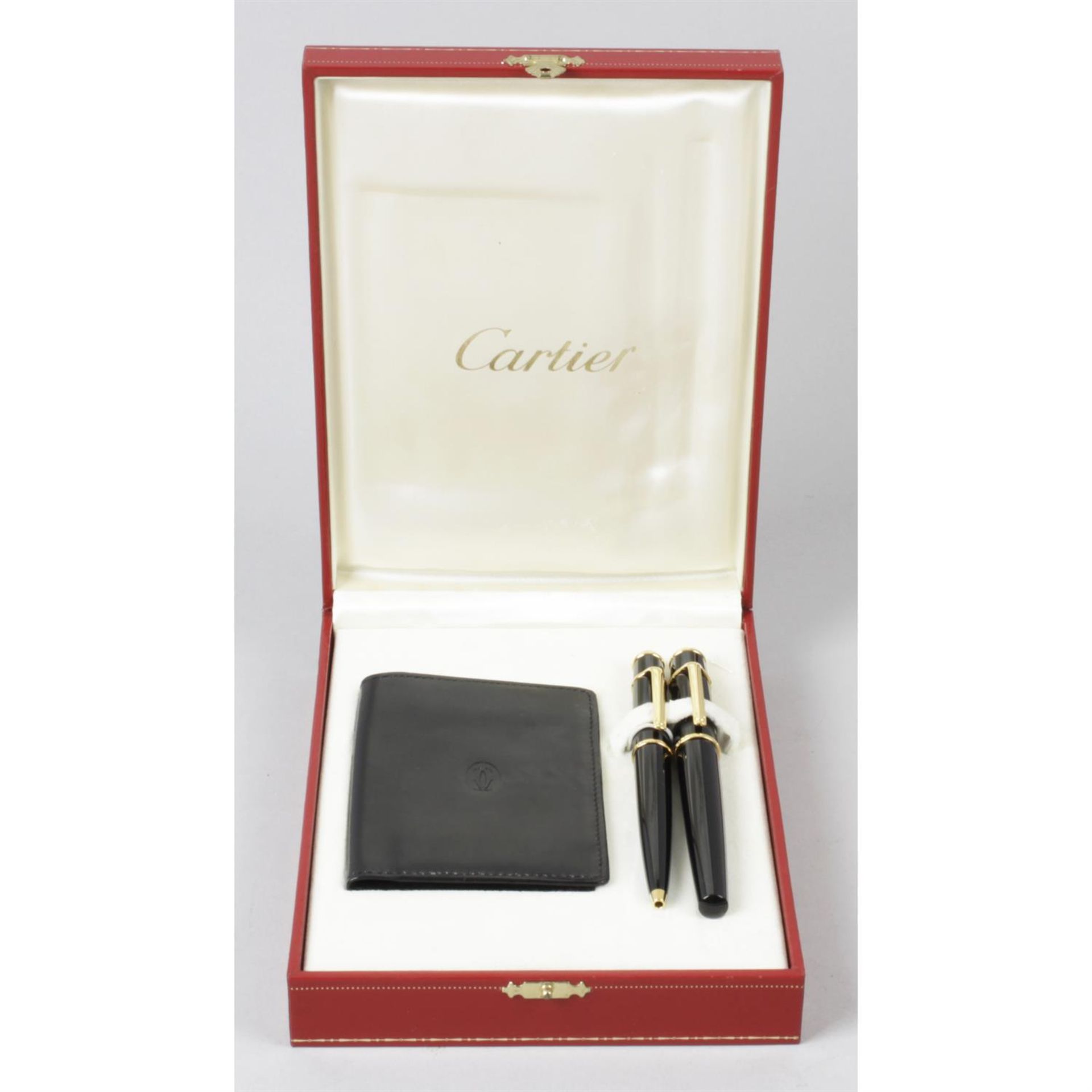 A Cartier 'Diabolo' ball point pen, a similar example, and a Cartier credit card case. (3)