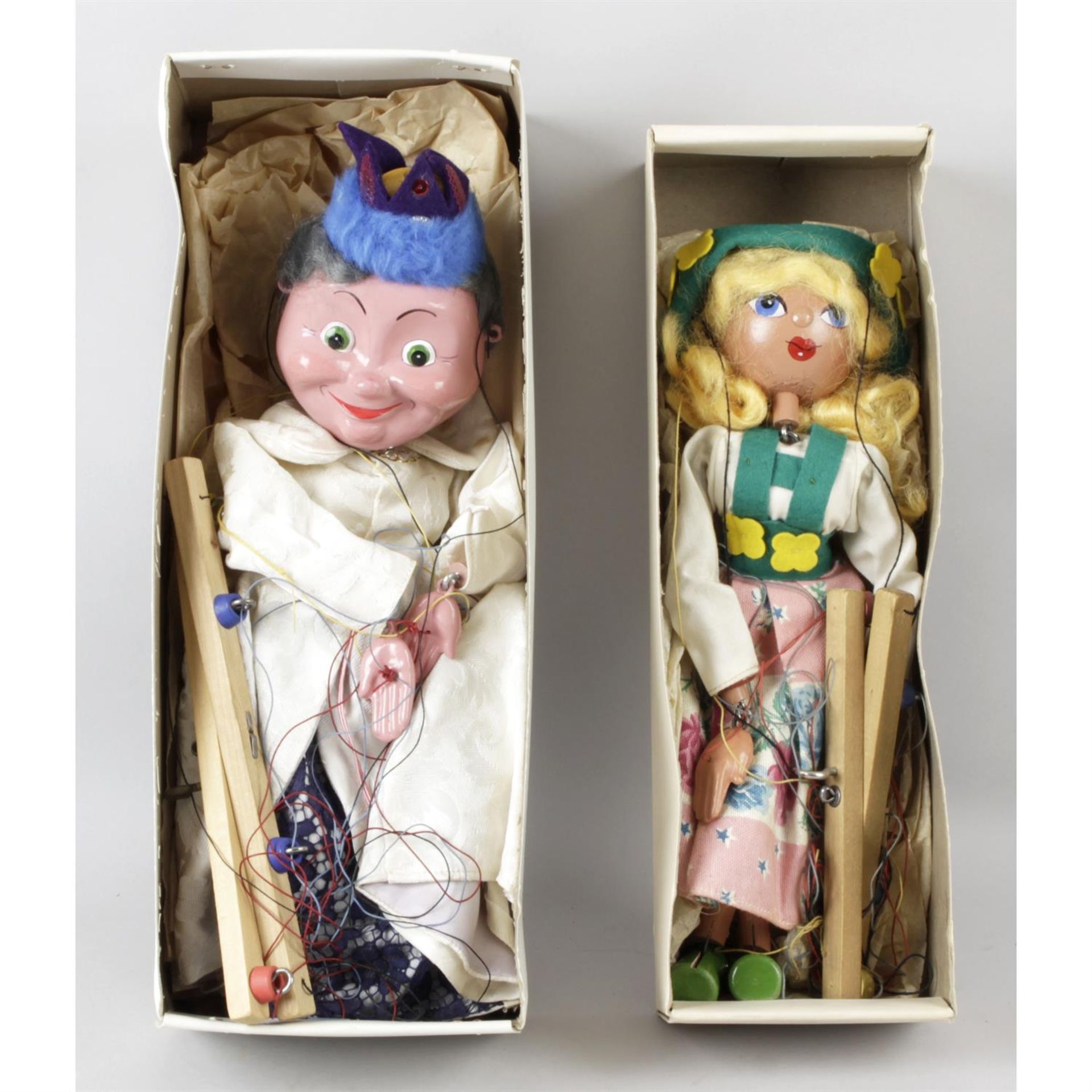 Two Pelham string puppets, two dolls and a selection of dolls clothes.