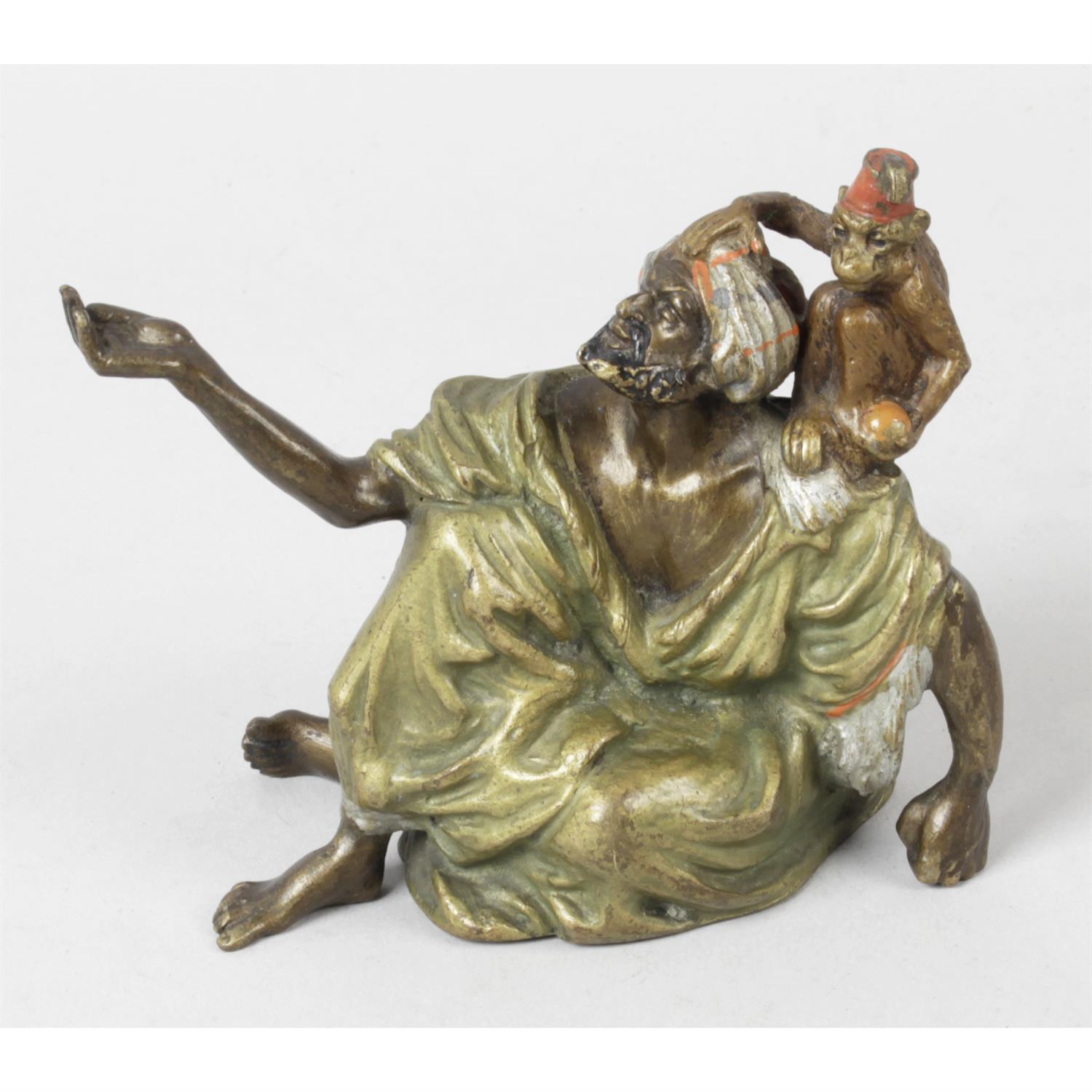 A cold painted bronze figured modelled as a seated male.