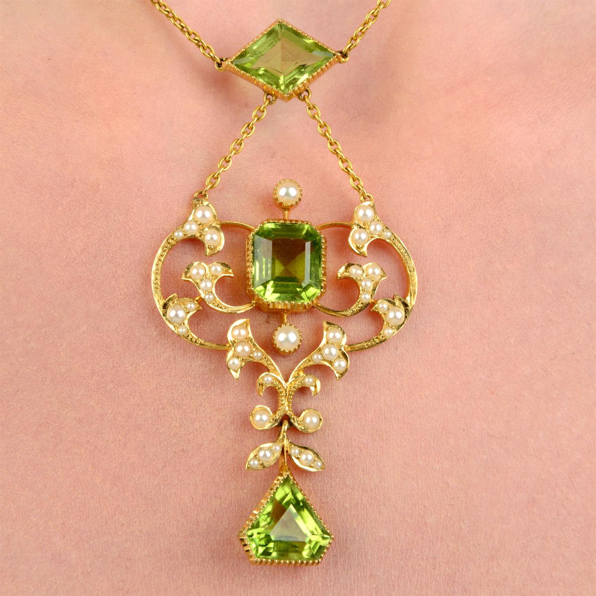An Edwardian 15ct gold peridot and split pearl pendant necklace, with fitted case.