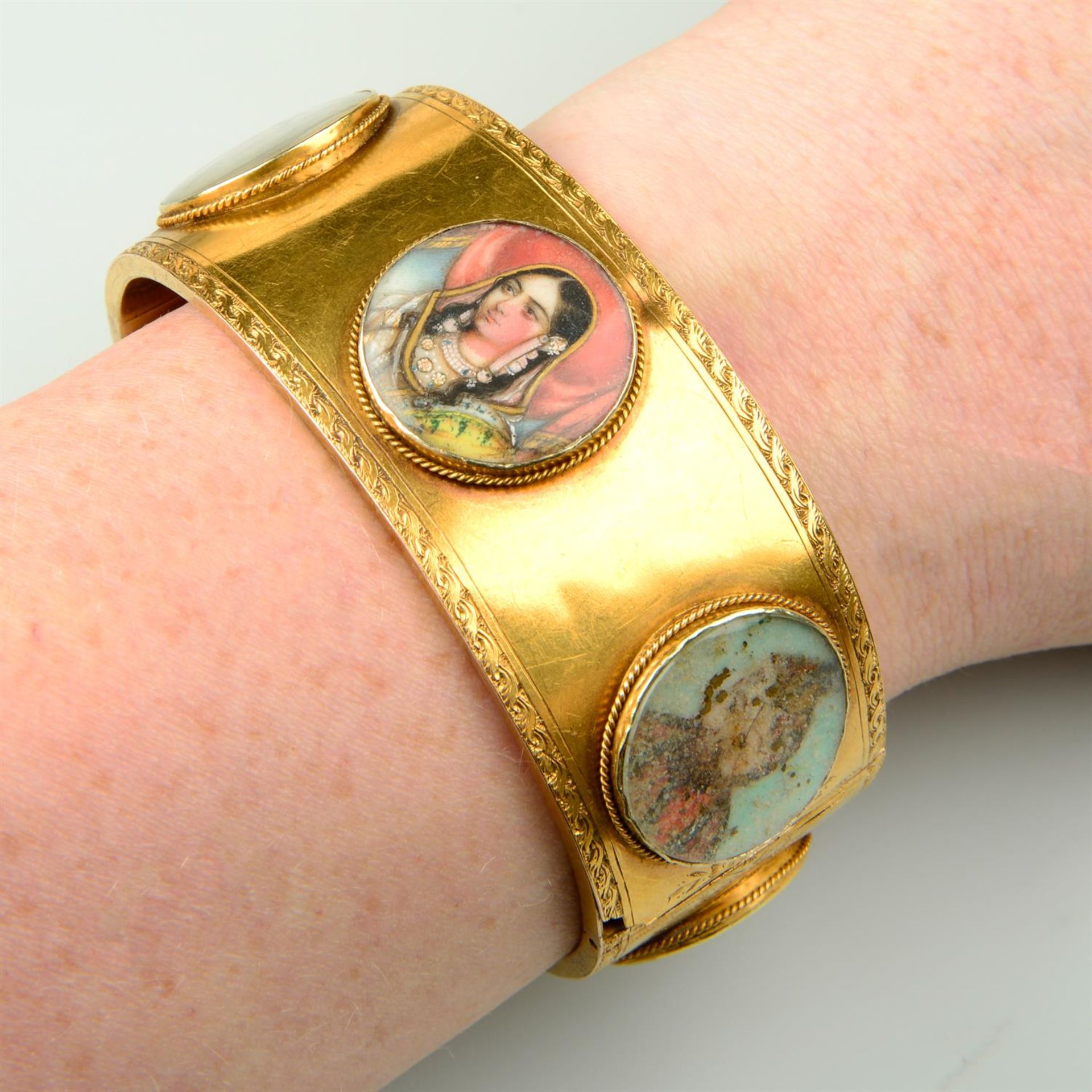 A mid 19th century gold hinged bangle, set with six Mughal portrait miniature glazed panels and