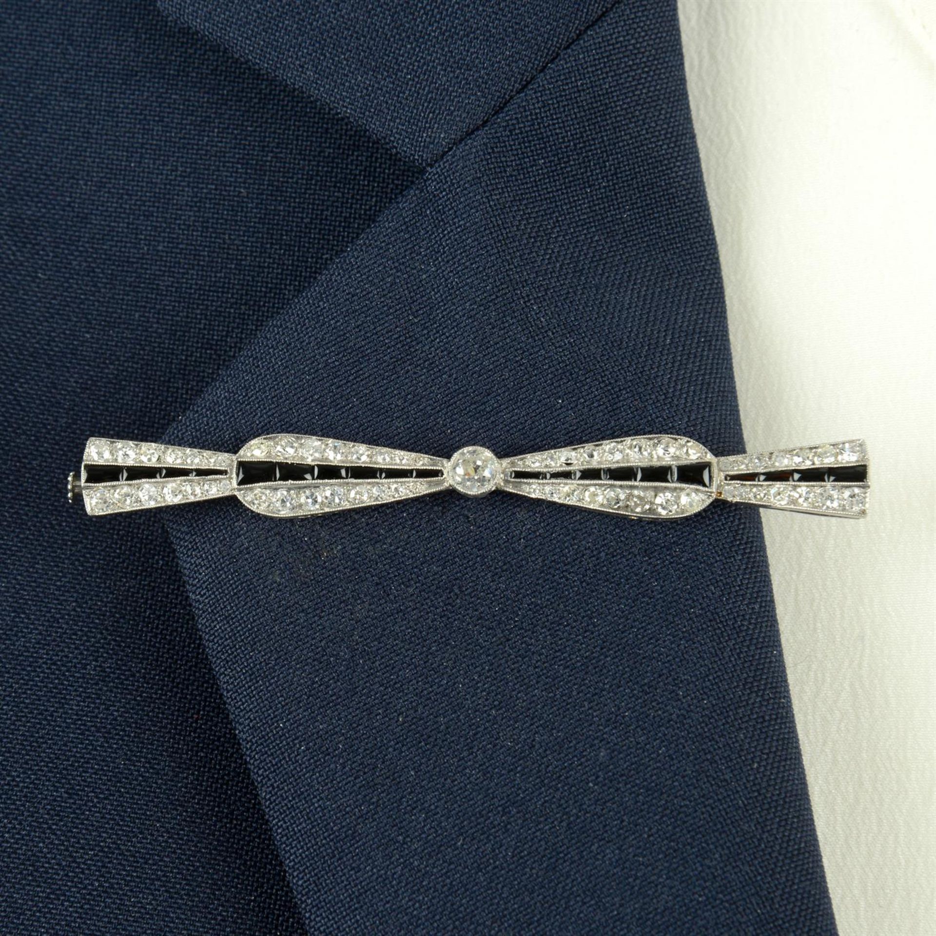 An Art Deco platinum, onyx old and single-cut diamond bow brooch.