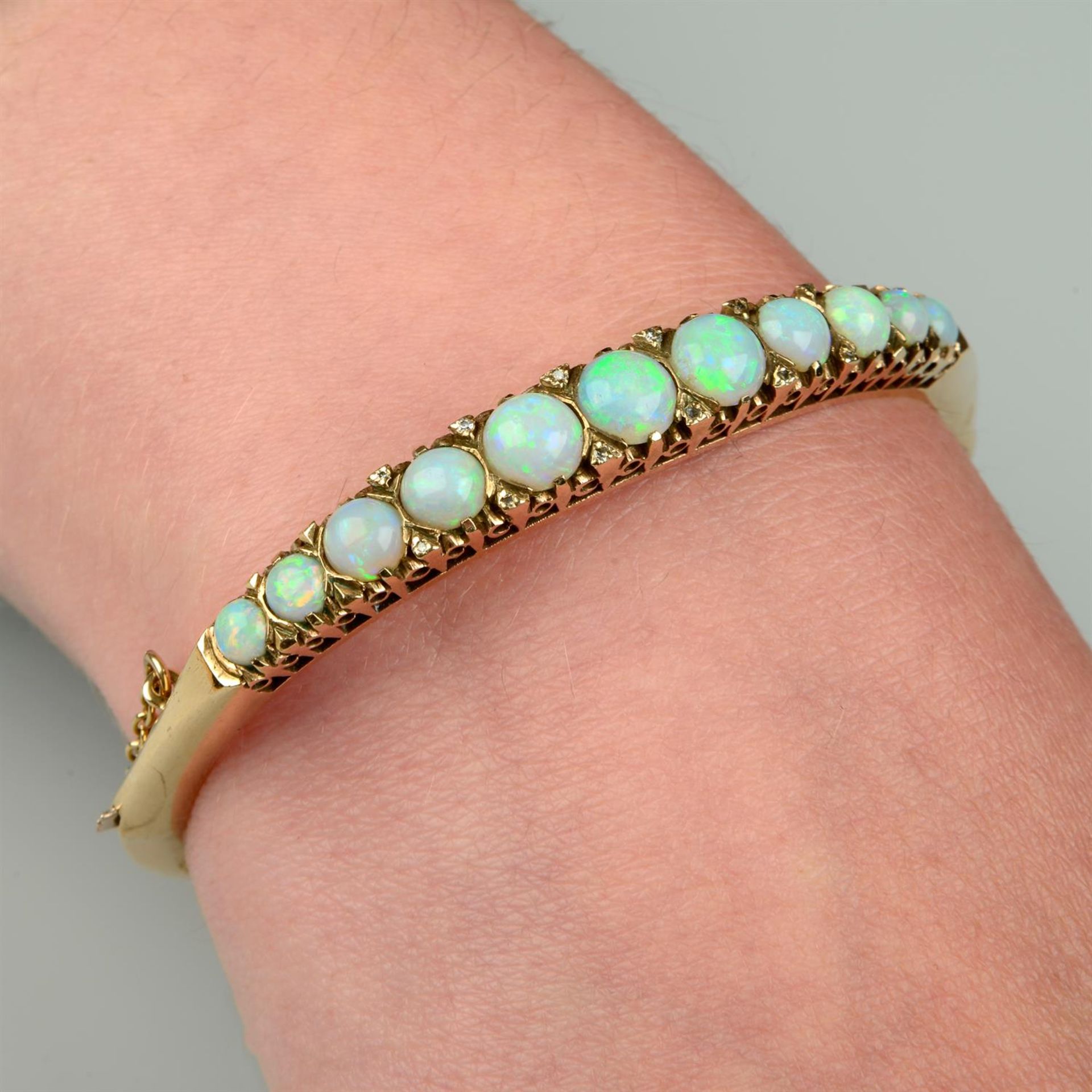 A 9ct gold opal and single-cut diamond spacer hinged bangle.