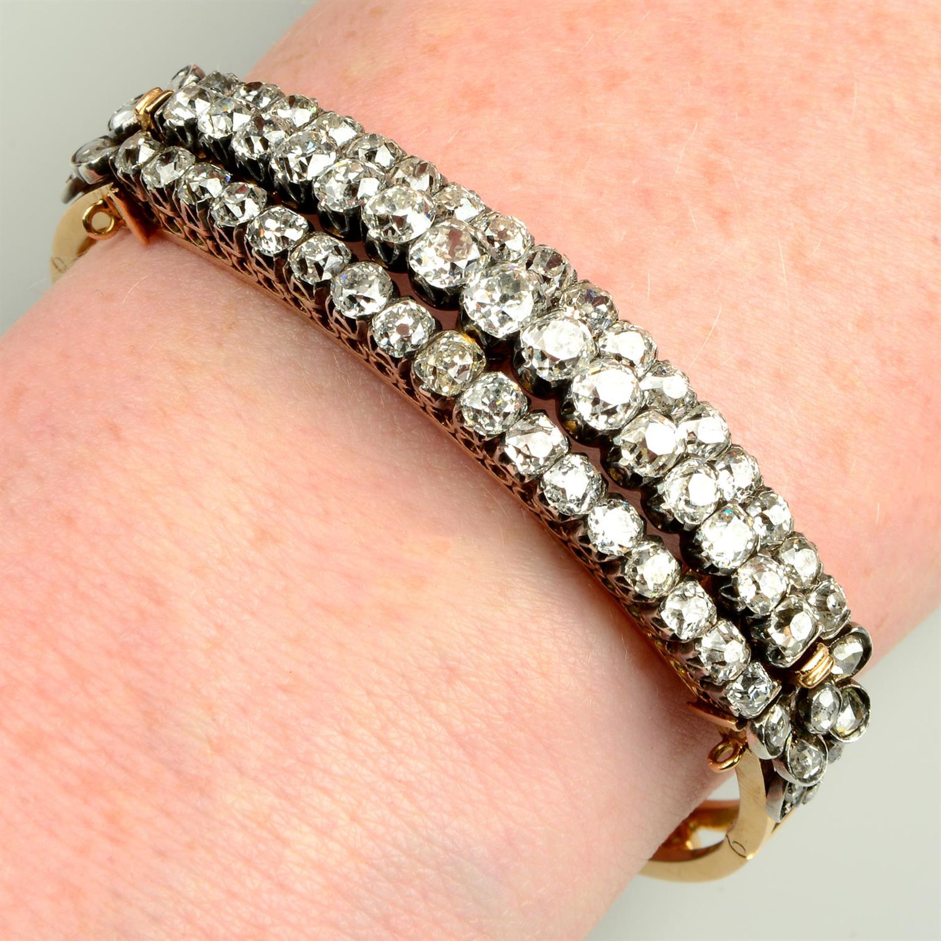 A late Victorian silver and 18ct gold old-cut diamond hinged bangle, may be worn as a brooch.