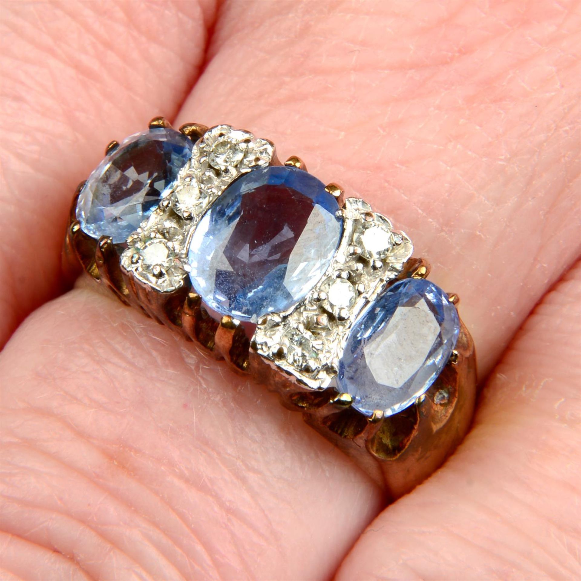 A 9ct gold sapphire three-stone ring, with brilliant-cut diamond spacers.