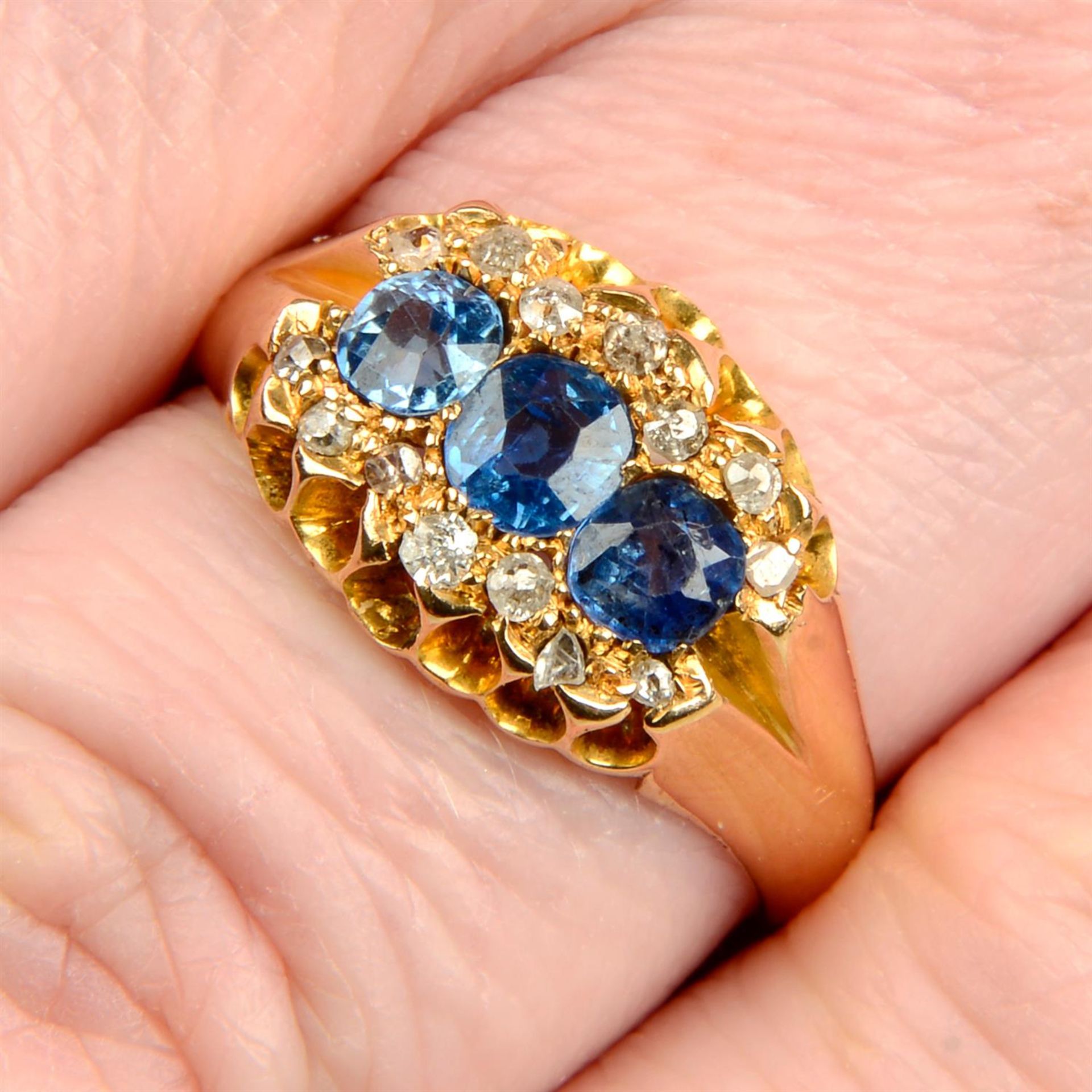 A late Victorian 18ct gold sapphire three-stone ring, with rose and old-cut diamond surround.